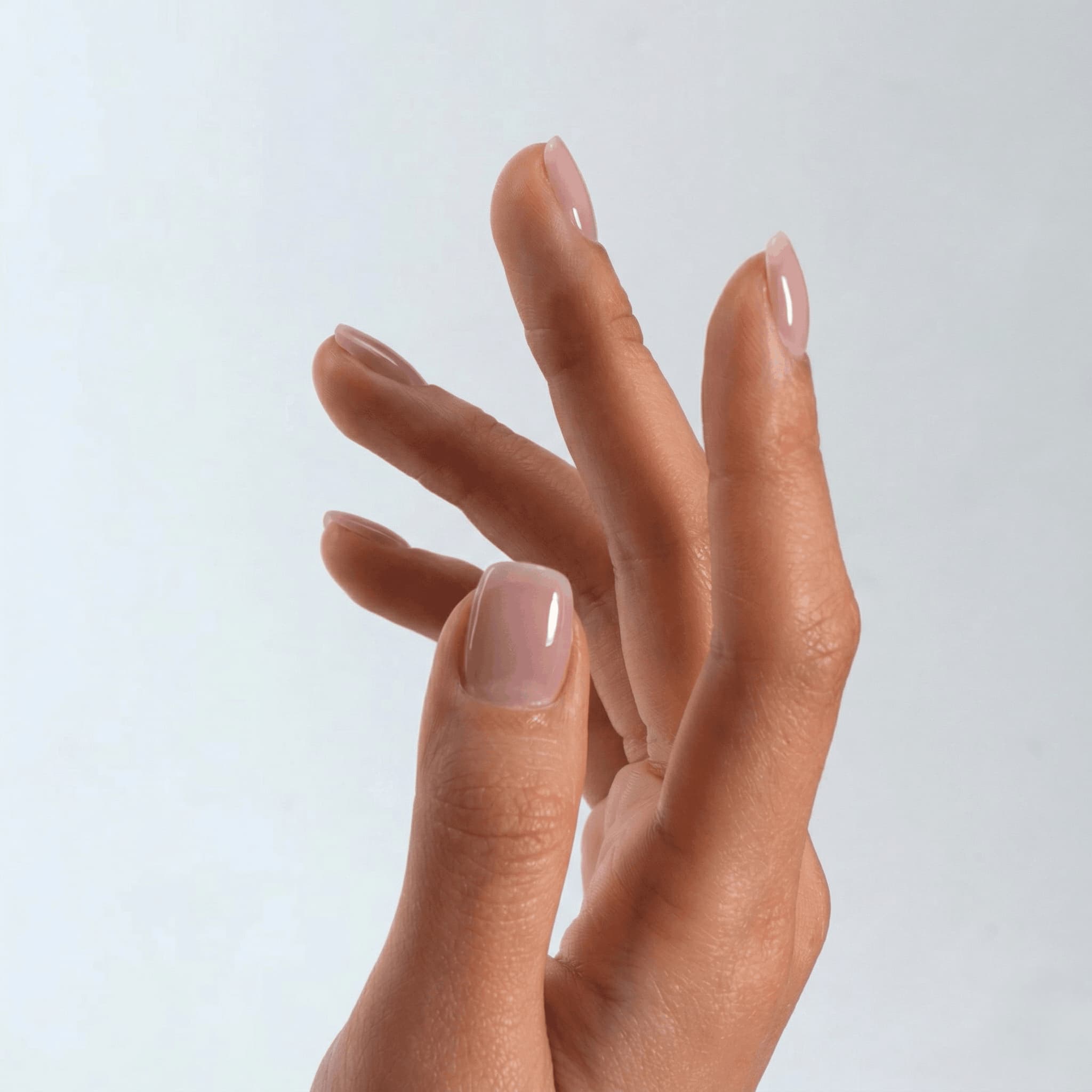 Hand with S&L Neutral pink nail polish on a plain background