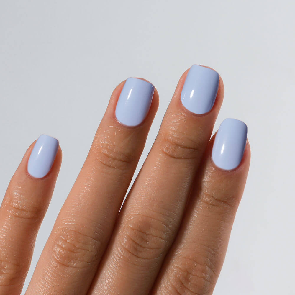 Hand with light blue nail polish on a plain background