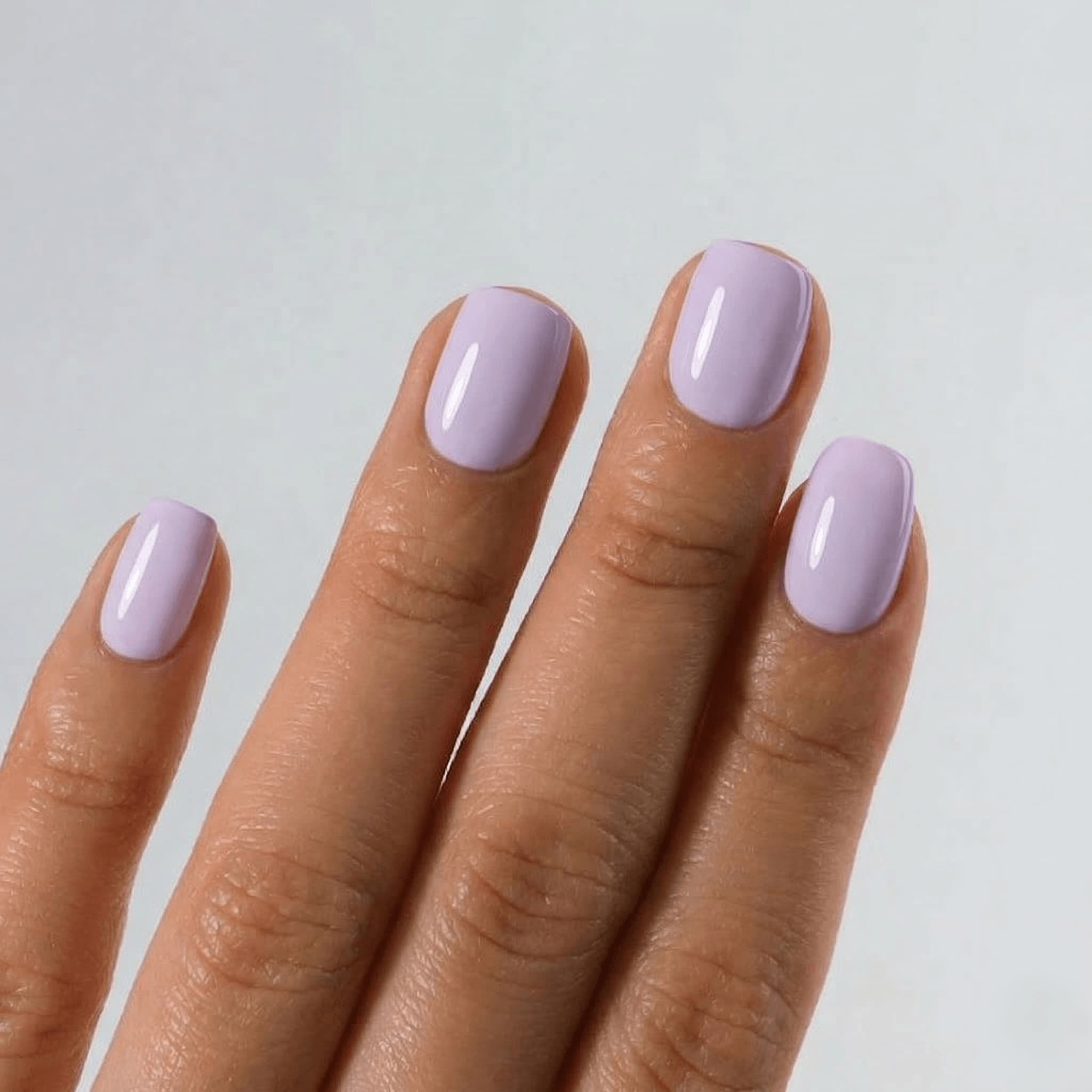 Hand with light purple nail polish on a plain background