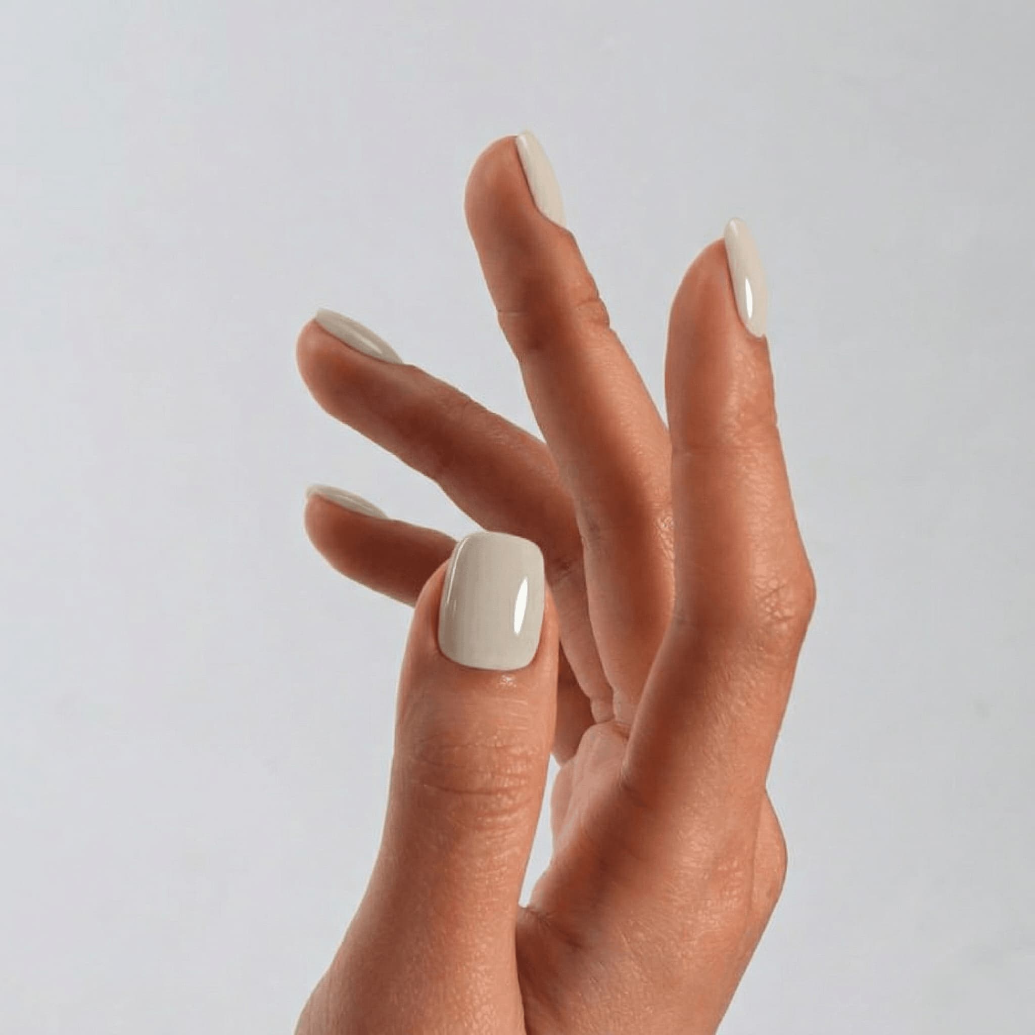 Hand with soft grey nail polish on a light gray background