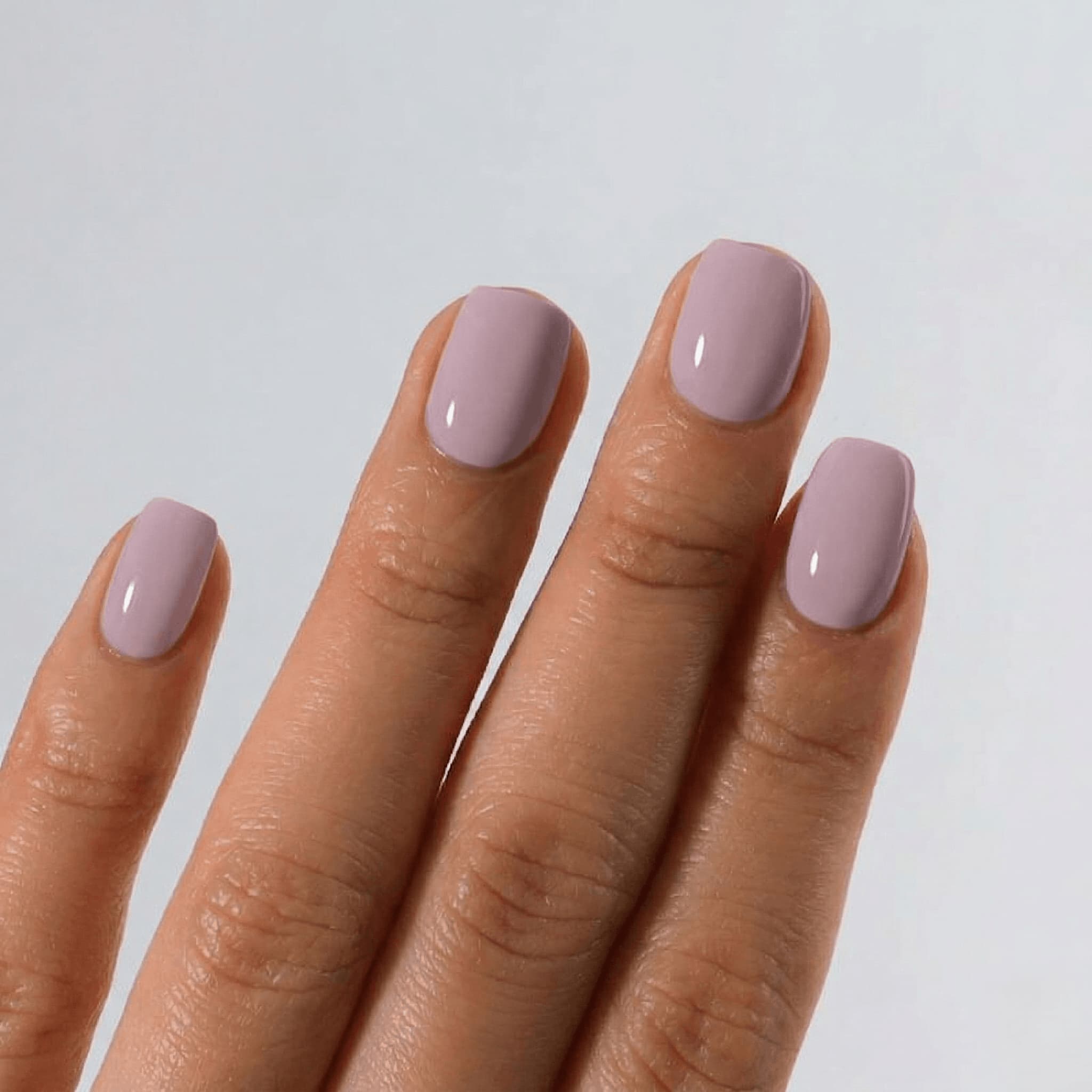 Hand with S&L light pink nail polish on a plain background