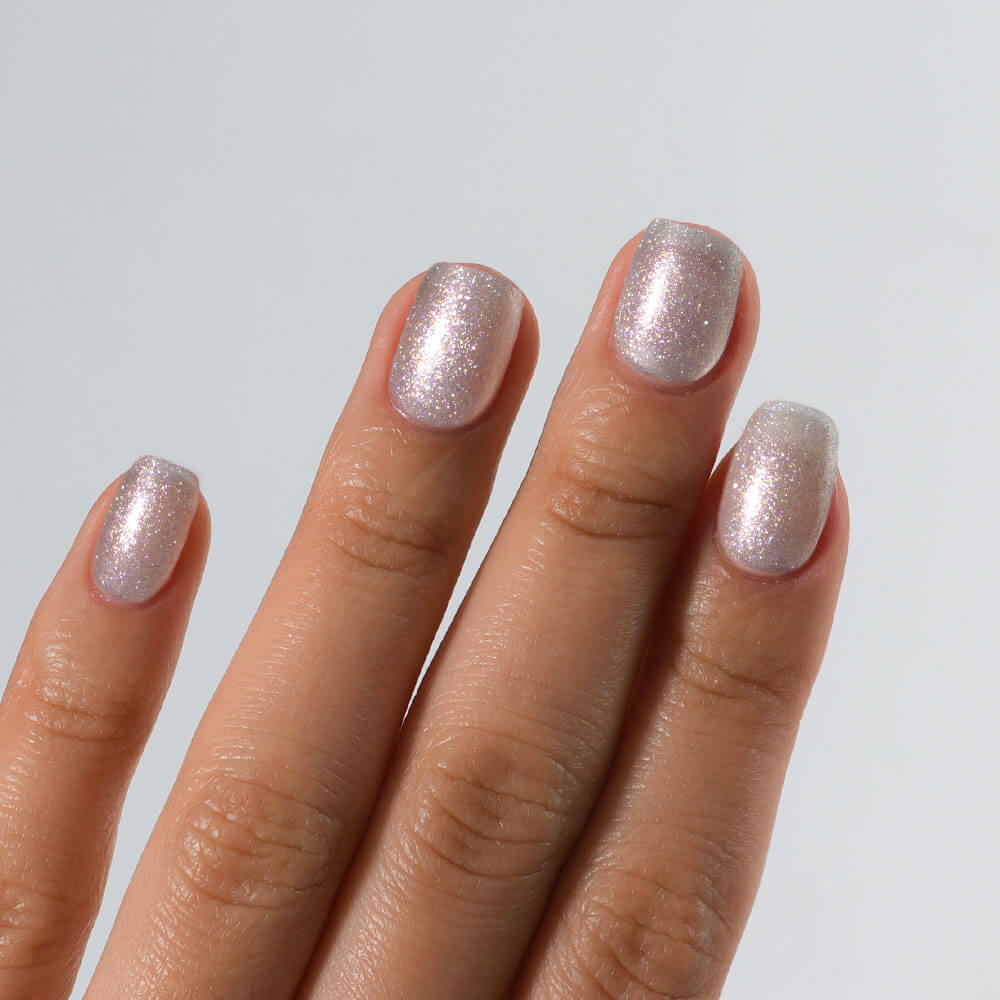 Hand with S&L dusty diamond glittery nail polish on a light gray background