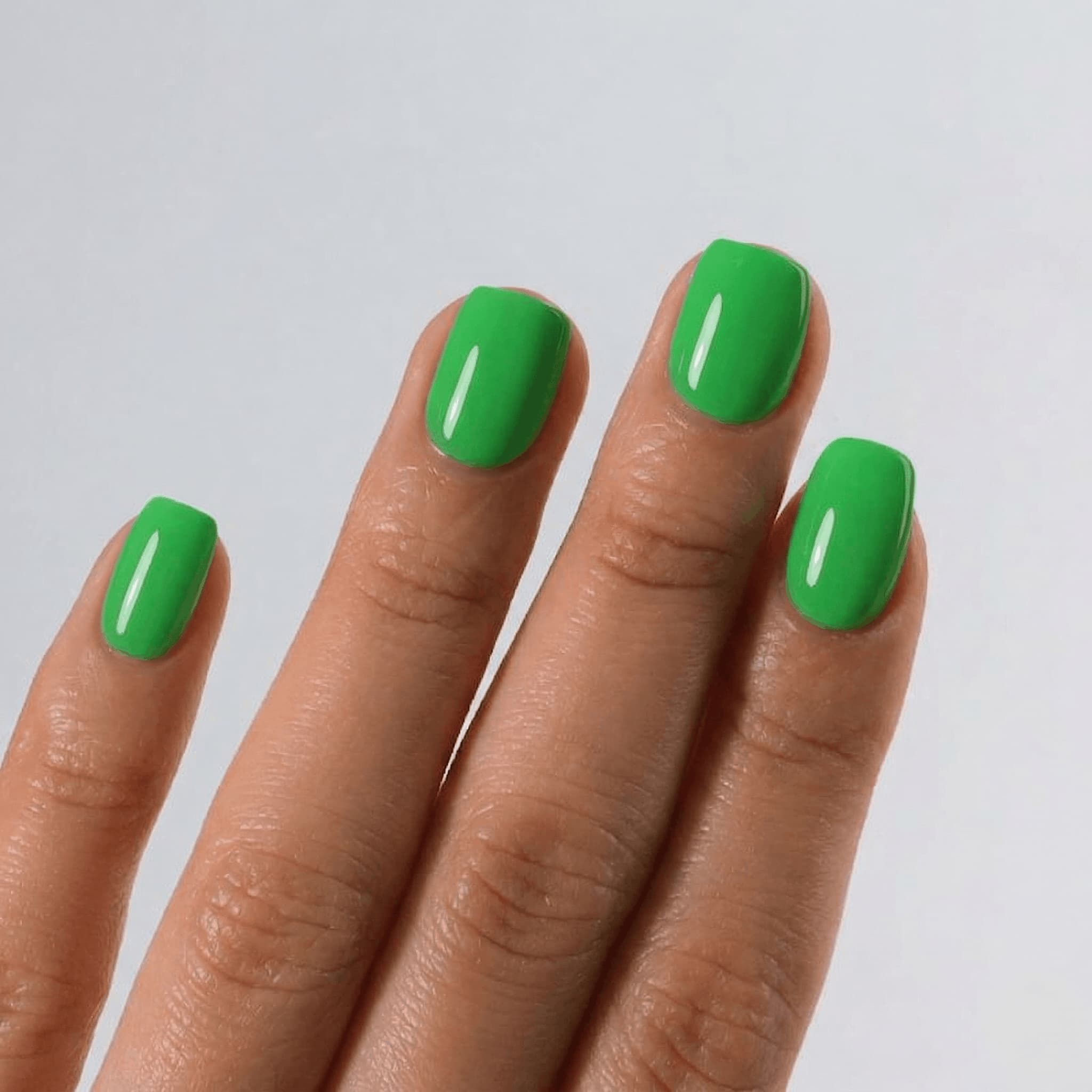 Hand with green nail polish on a plain background