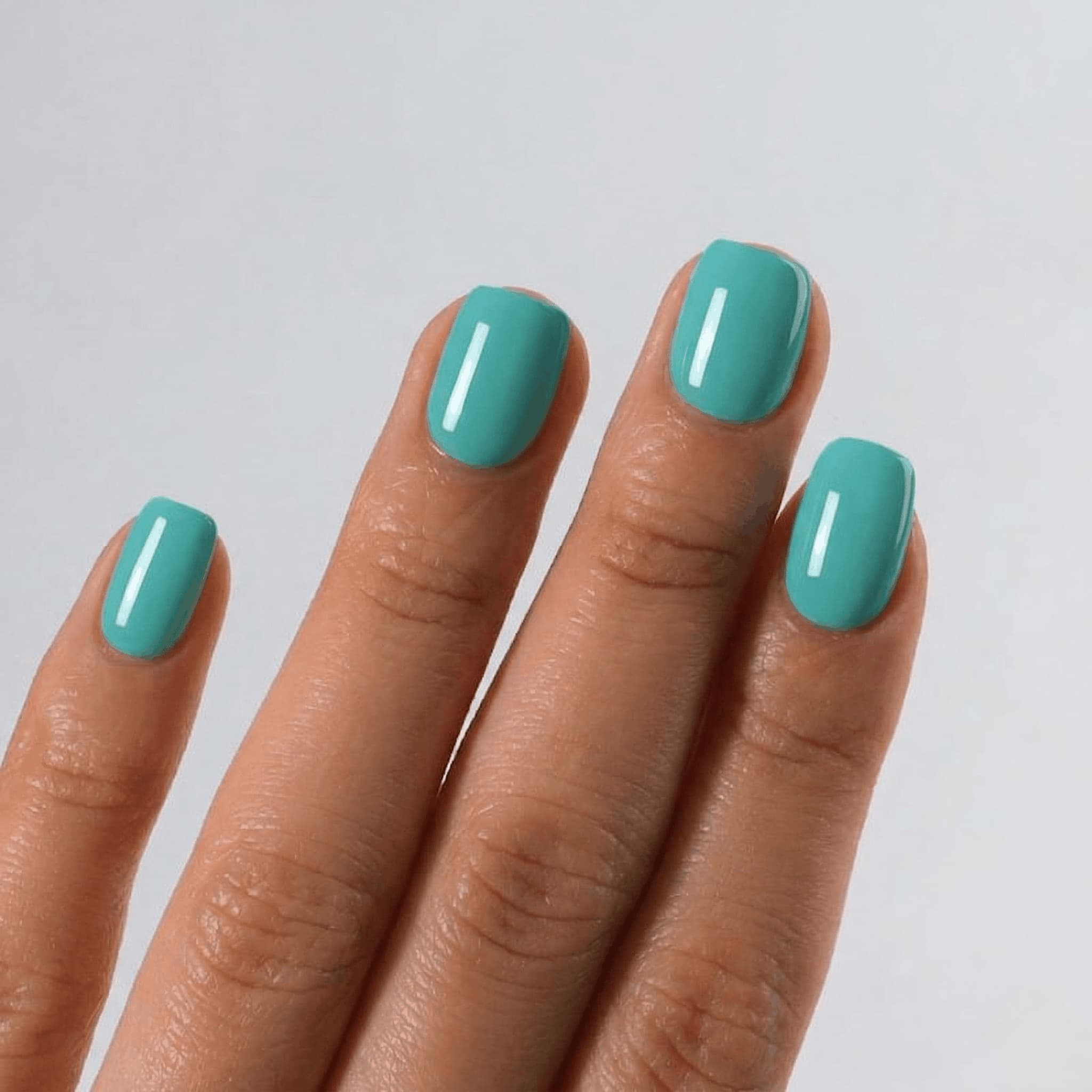 Hand with teal nail polish on a light gray background