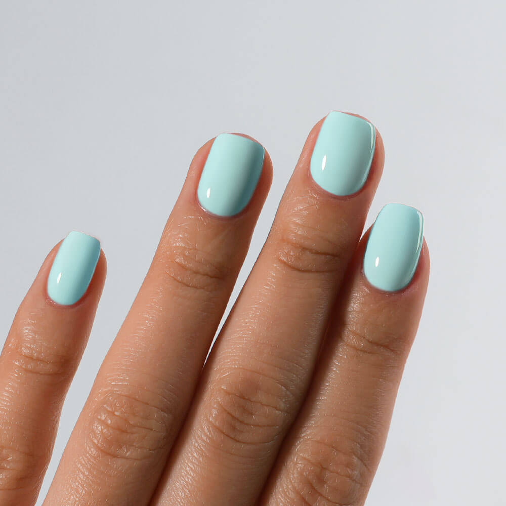Hand with light blue nail polish on a plain background