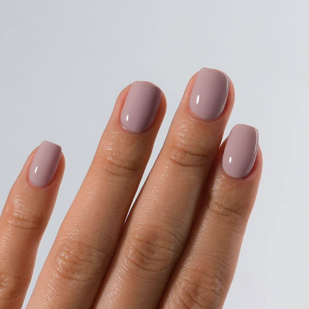 Hand with S&L light pink nail polish on a plain background