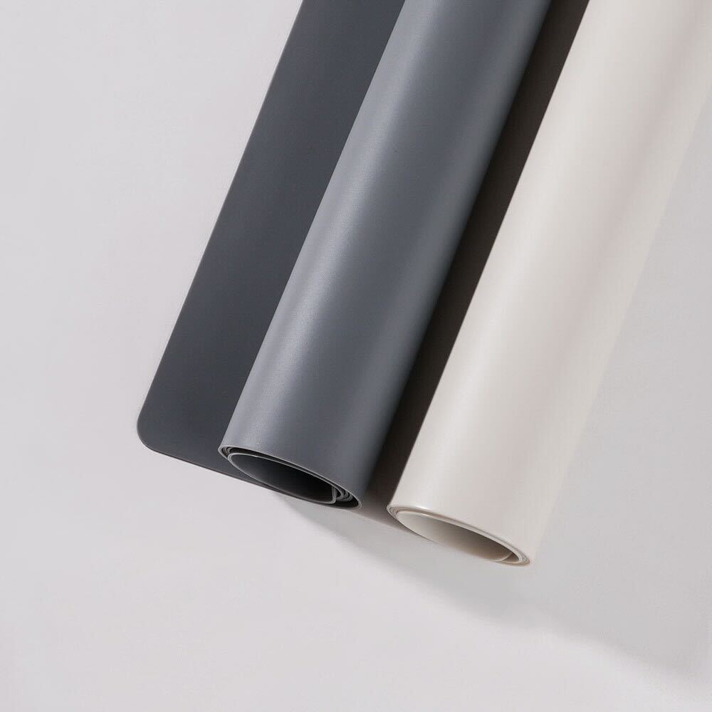Two rolls of silicone mat, one dark gray and one beige, on a white background.